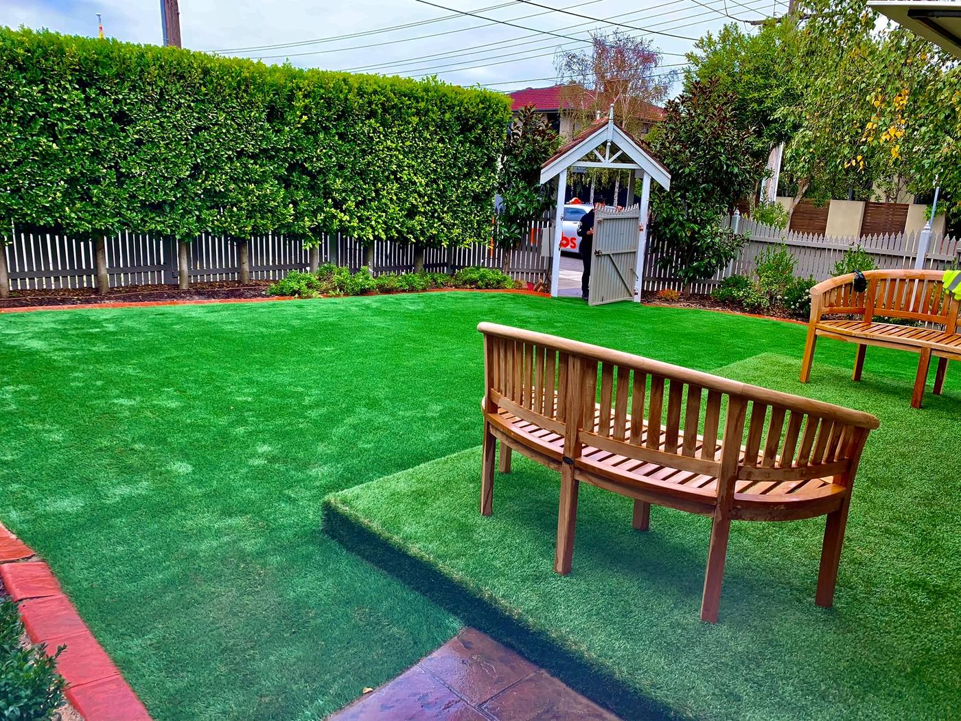 Artificial turf backyard in West Melbourne with a raised turf platform and timber benches